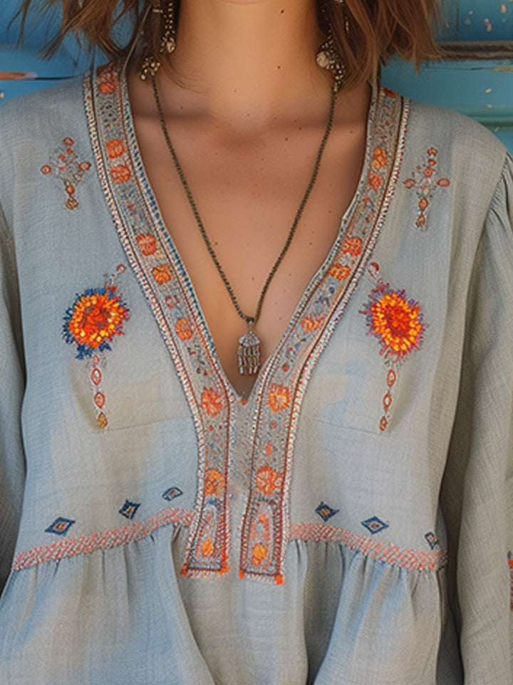 Close-up of V-neckline on women's light blue embroidered blouse, showing floral details