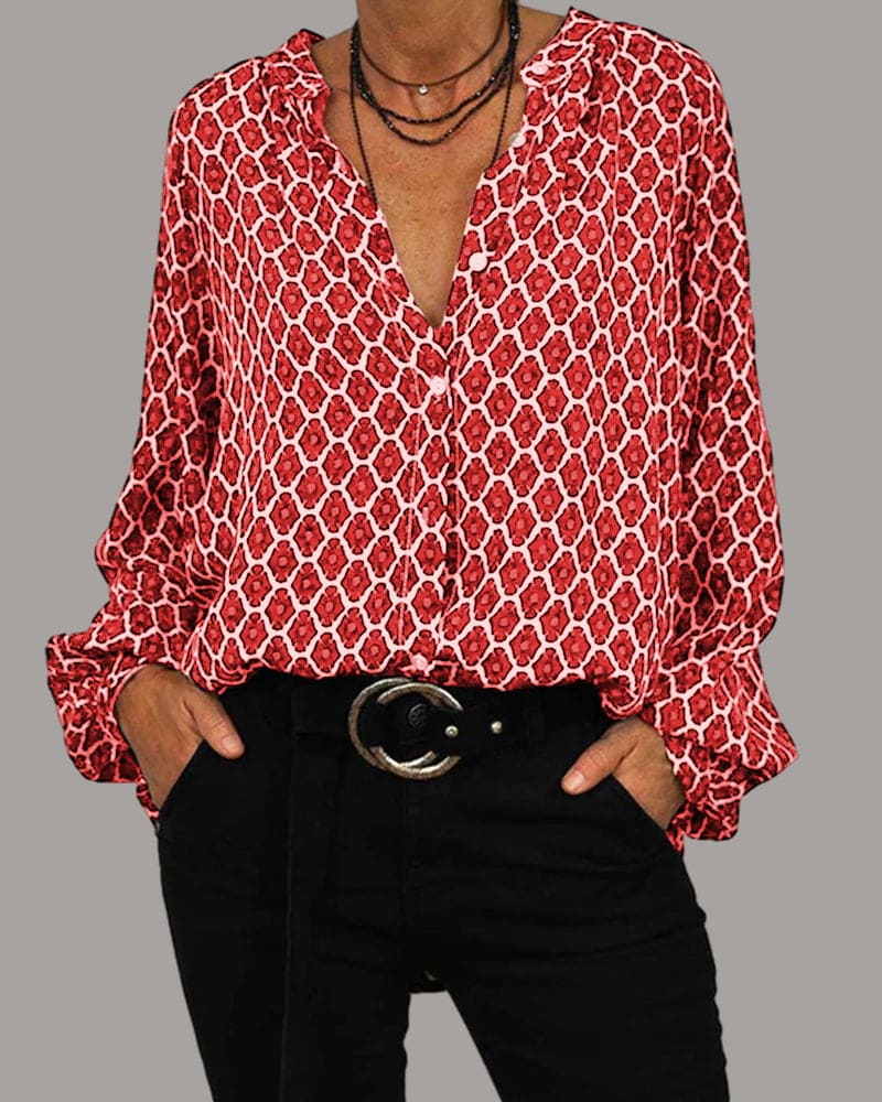 Women red geometric print long sleeve blouse with v-neck and button closure, styled with black pants.