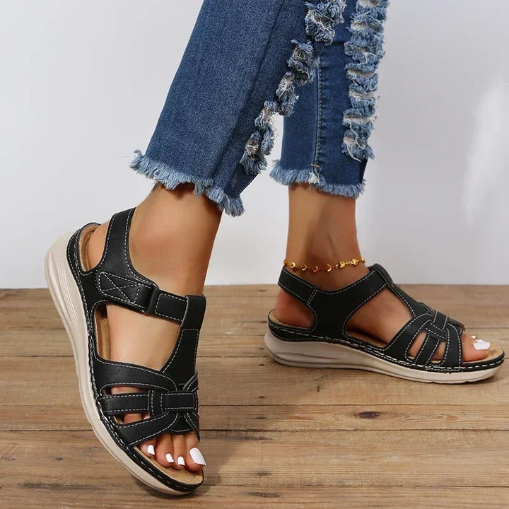 Women's black T-strap buckle ankle sandals, side angle showing comfortable sole design