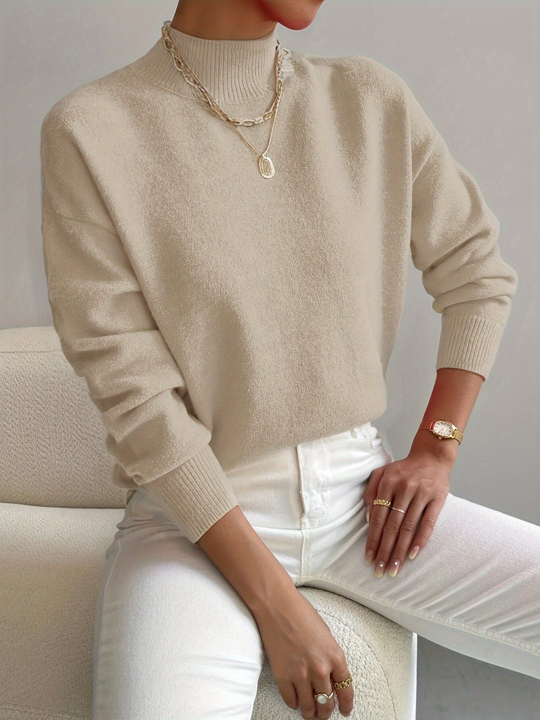 Women beige turtleneck knit sweater with long sleeves and ribbed cuffs, worn by model.