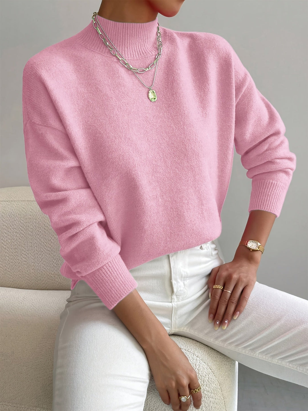 Women pink turtleneck knit sweater with long sleeves and ribbed cuffs, upper body focus.