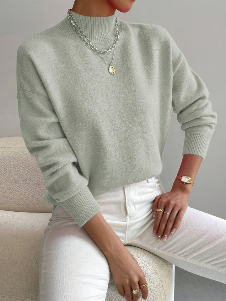 Women light green turtleneck knit sweater with long sleeves and ribbed cuffs, front view.