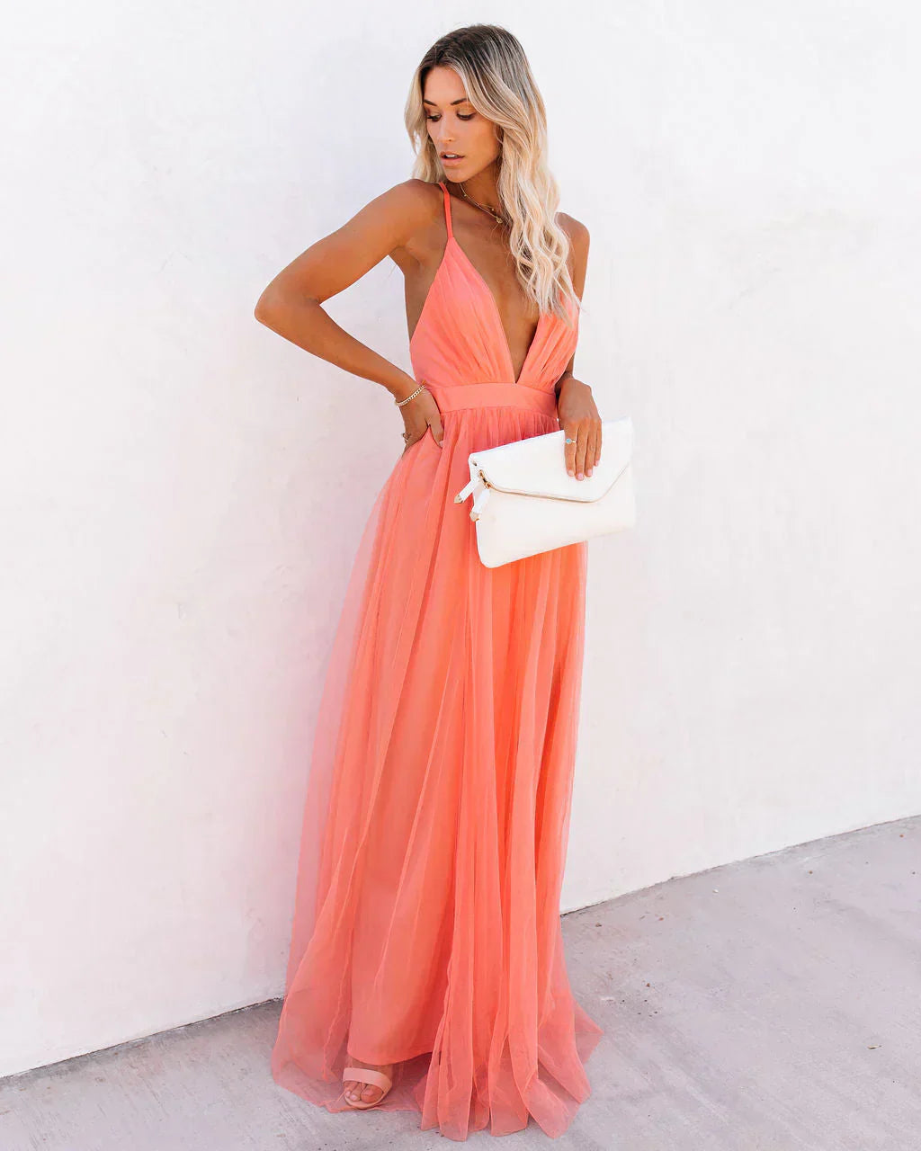 Women peach V-neck maxi dress with fitted bodice and flowing skirt, holding clutch
