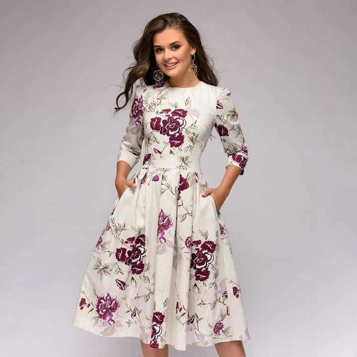 Women white midi dress with purple floral print, round neck, three-quarter sleeves, and side pockets shown from the front.