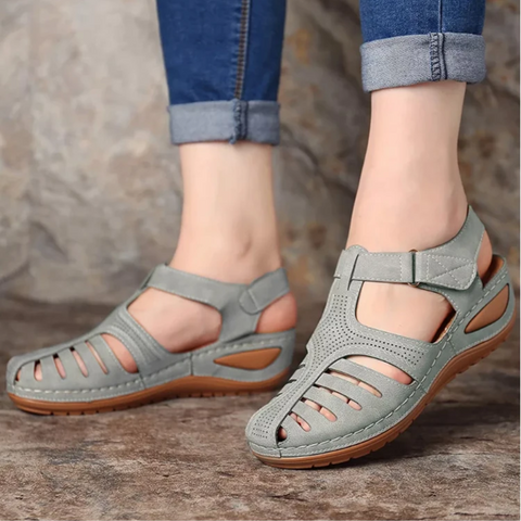 Women's light gray strappy closed toe sandals with wedge heel and hook-and-loop closure on a model's feet