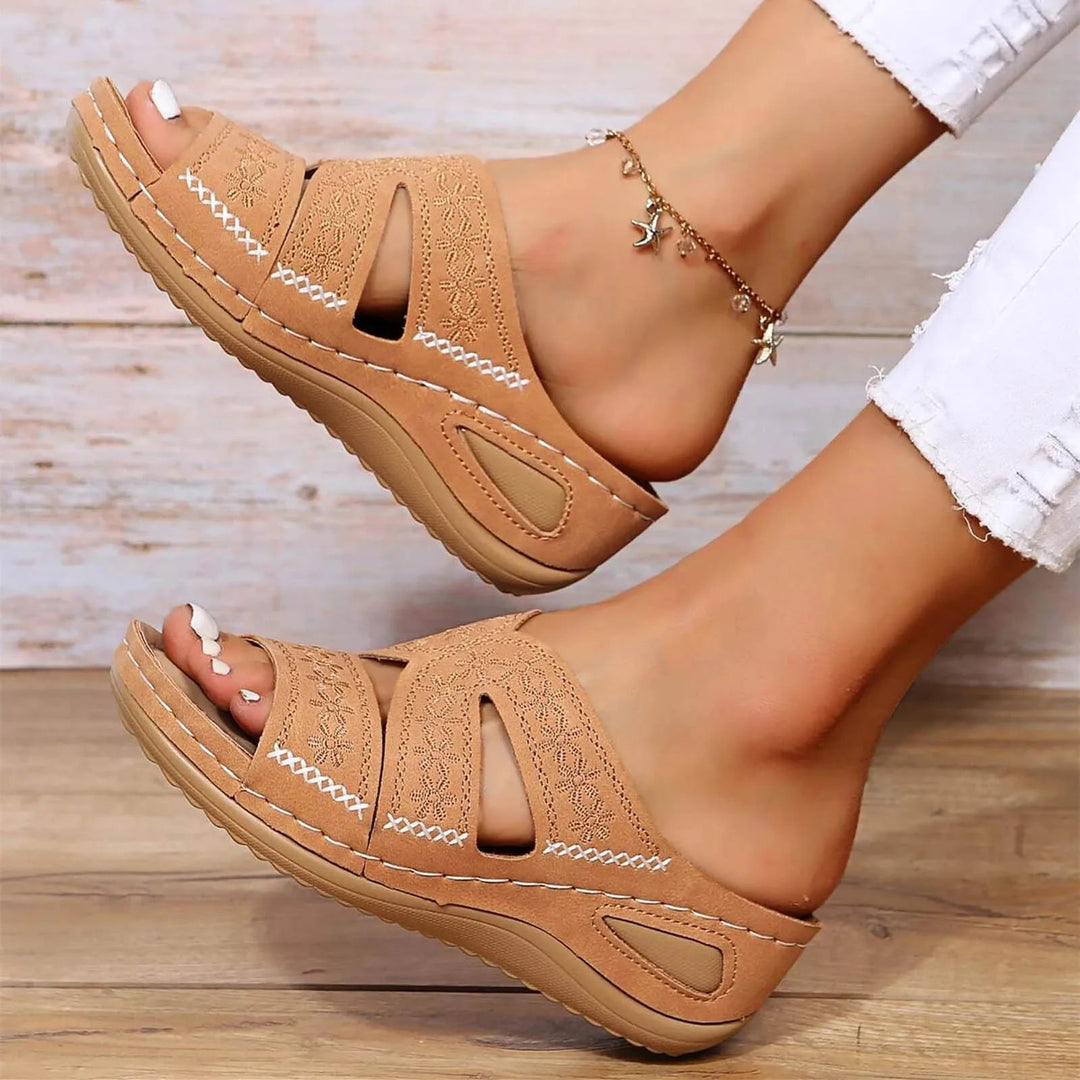 Tan wedge platform slides with embroidered straps shown from above with white stitching detail