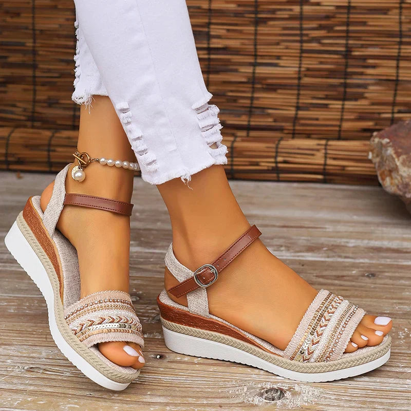 Side view of woven wedge sandals featuring cognac leather strap and cream patterned toe band