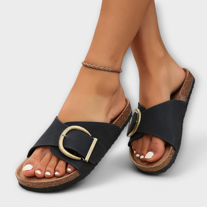 Black buckle slide sandals with cork footbed worn on feet
