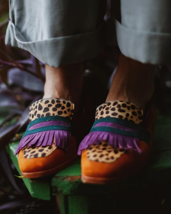 Women leopard print colorblock fringe loafers with purple and teal bands on feet