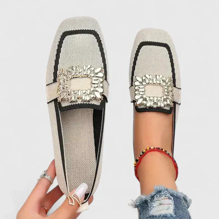 Cream and black ruffled trim loafers with beige bow accent on foot
