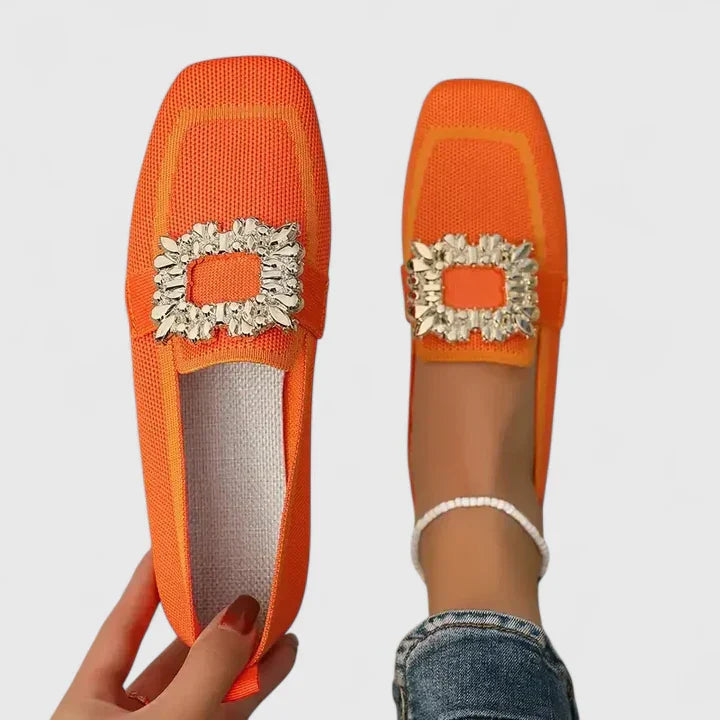 Bright orange loafers with cream ruffled trim and square bow on foot