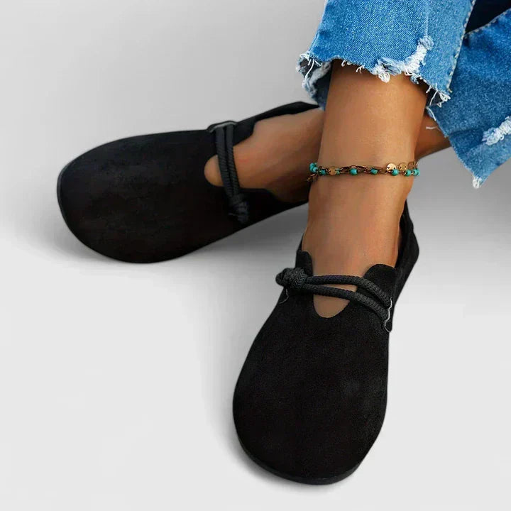 Black suede loafer flats with rope accent worn with distressed blue jeans