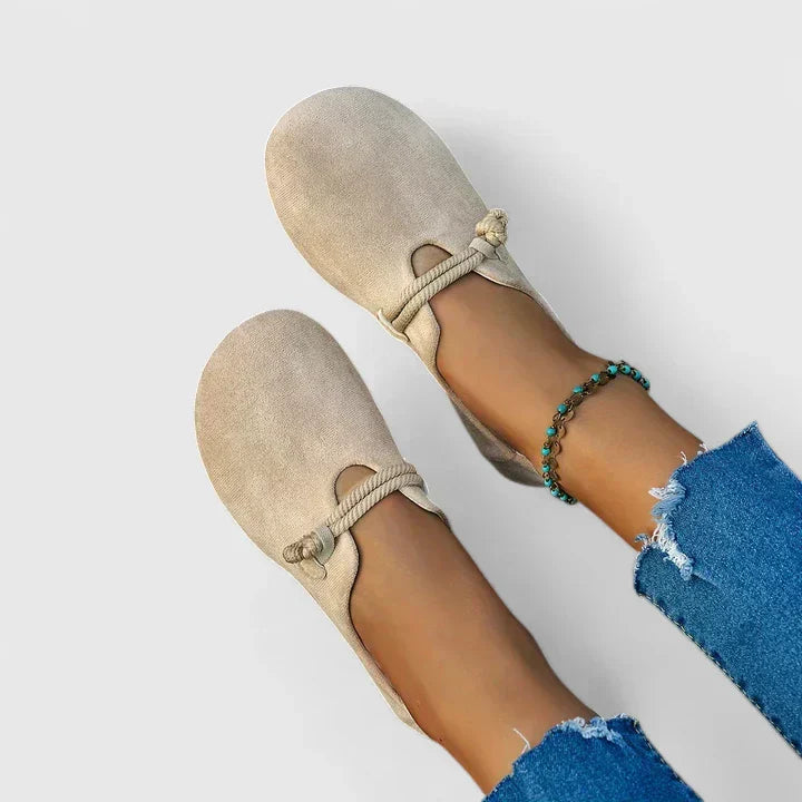 Beige suede slip-on loafers with knotted rope detail on feet, overhead view