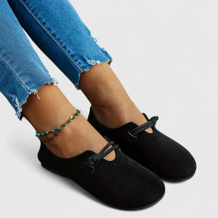 Black suede slip-on loafer flats with rope knot detail, styled with distressed jeans