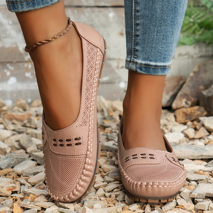 Beige perforated moc toe loafer flat with quilted sole and decorative perforations on upper
