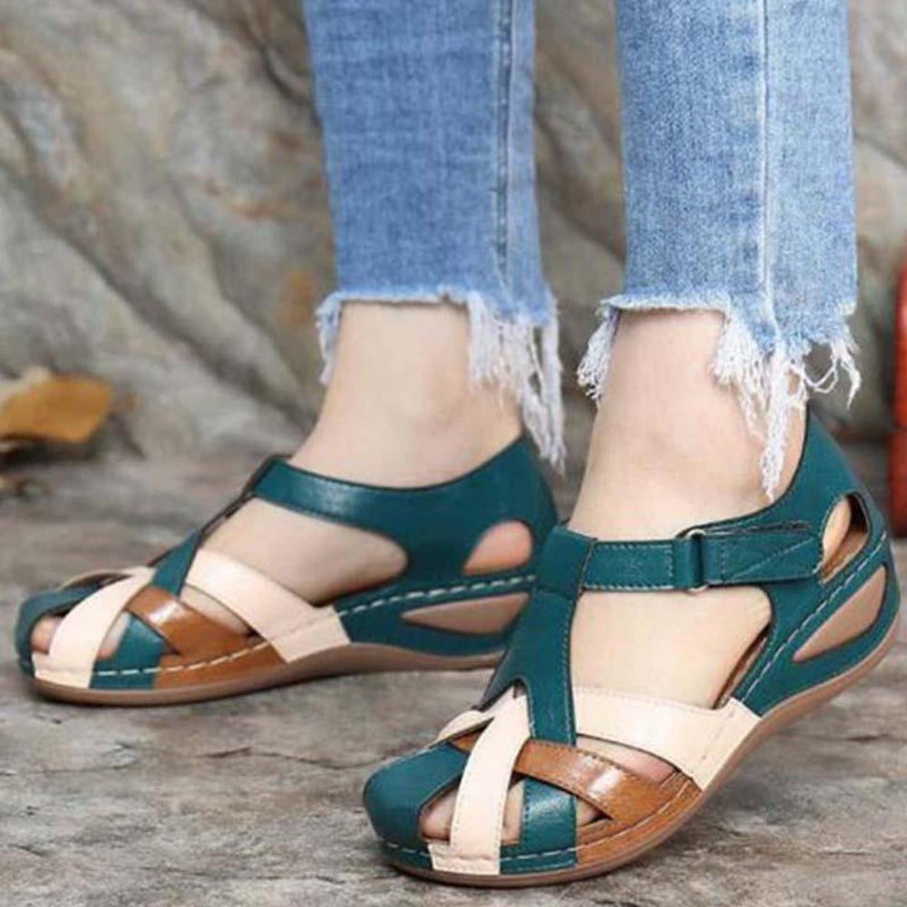 Women teal and beige colorblock closed toe wedge sandals with woven straps, front view on feet.