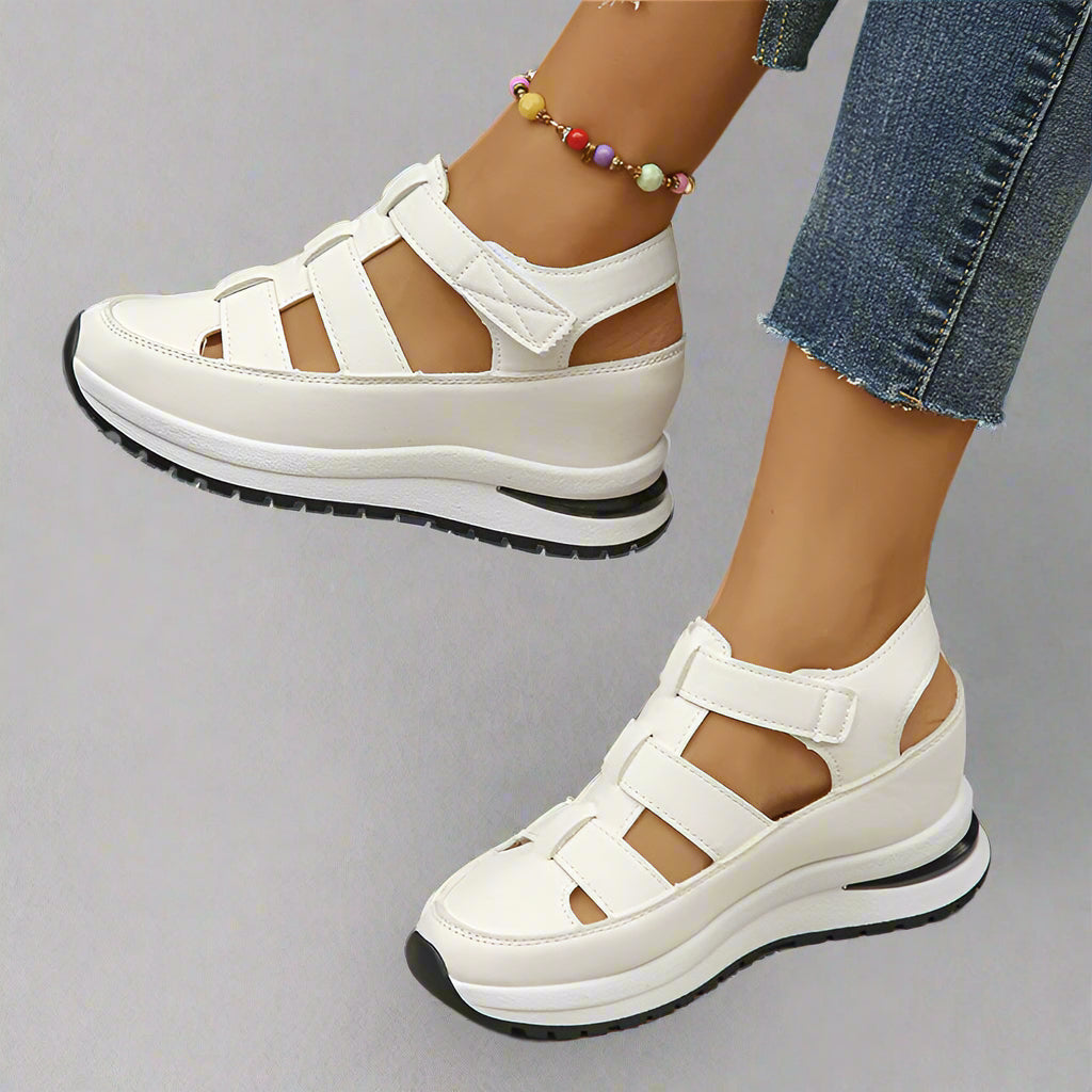 Women white platform cutout sneakers with hook-and-loop straps, side view on model with jeans