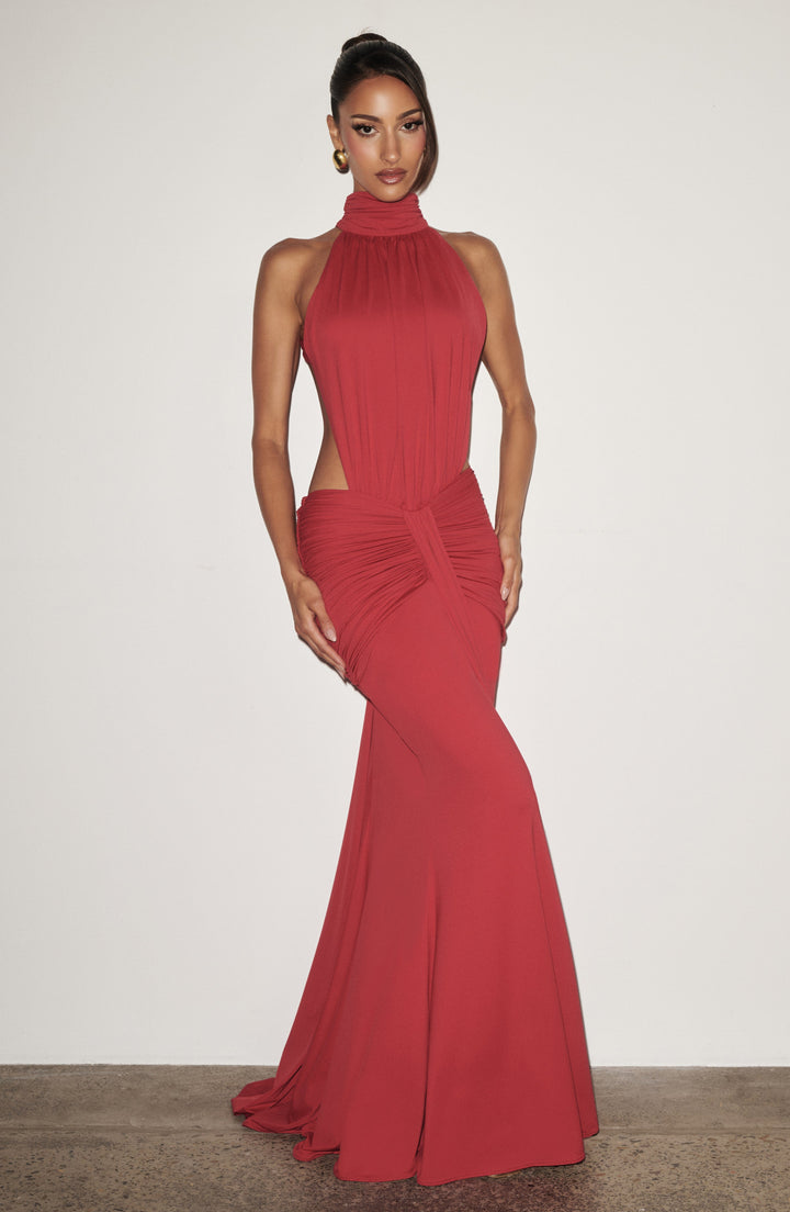 Women red halter backless maxi dress in a fitted silhouette against a white wall, full view