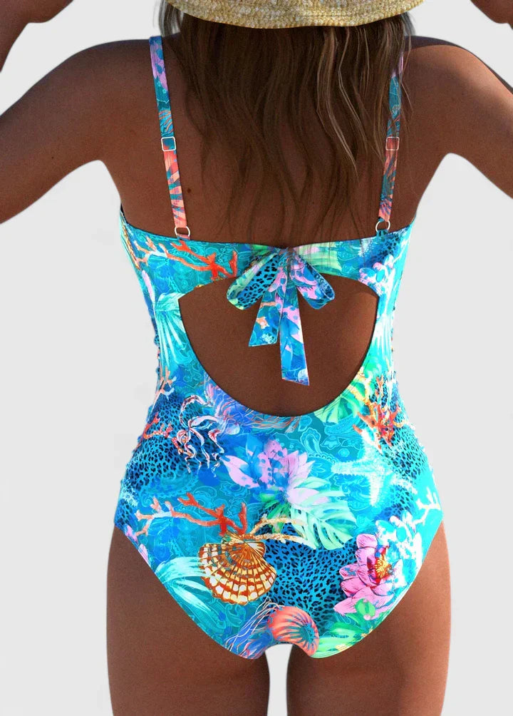Back view of tropical printed one-piece swimsuit showing tie-back closure with colorful floral and coral print